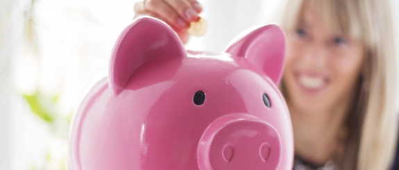 Rosa Sparschwein mit Münzen im Hintergrund, Konzept für Ersparnisse und Finanzplanung