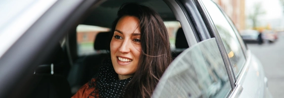 Frau fährt mit geöffnetem Autofenster durch die Stadt.