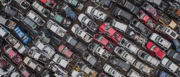 Luftaufnahme eines Schrottplatz mit beschädigten Autos in Reihen.