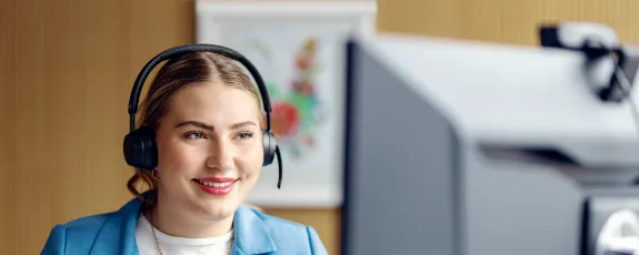 Junge Frau mit Headset vor einem Bildschirm in einer digitalen Beratungssituation.