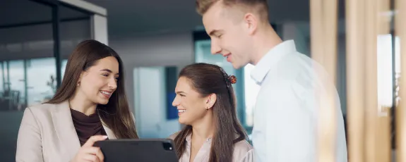 Drei dualer Studentinnen und Studenten tauschen sich an einem Tablet aus.