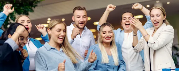 Jubelnde Nachwuchskräfte spielen gemeinschaftlich Tischfußball und genießen eine entspannte Pause in einem modernen Büro.