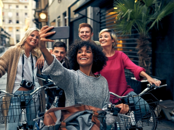 Fünf Freunde mit Fahrrädern lachen zusammen in einer Fußgängerzone einer Stadt