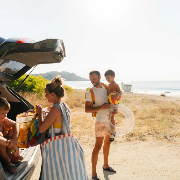 Eine Familie genießt den Urlaub mit dem Auto am Strand.