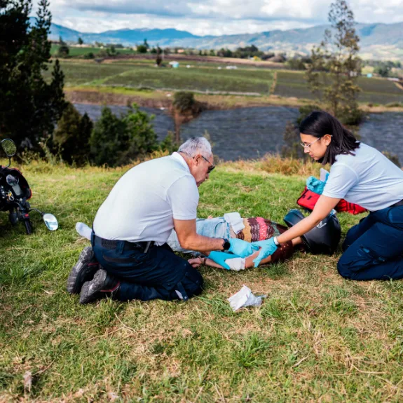 Ein Mann und eine Frau leisten Erste HIlfe bei einer Motorradfahrerin, die einen Unfall hatte.