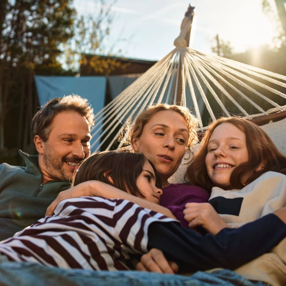 Eine Familie liegt gemütlich in einer Hängematte.