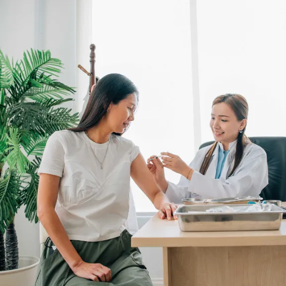 Eine Ärztin impft eine Frau gegen Gürtelrose.