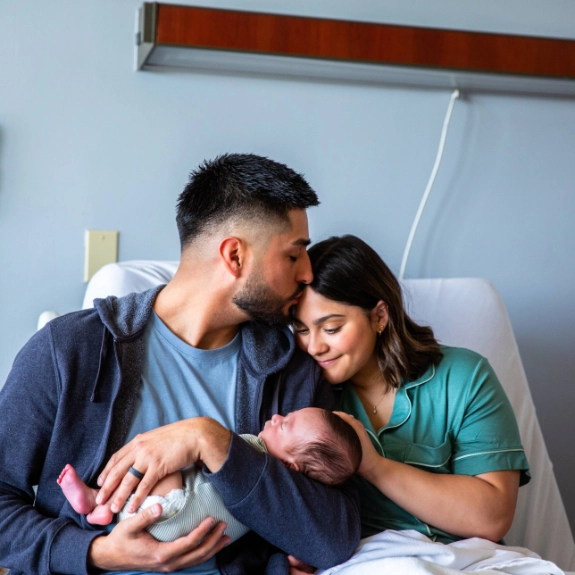 Glückliche Eltern im Krankenhaus halten im Krankenhaus ihr neugeborenes Baby im Arm.