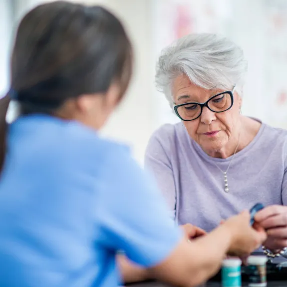 Beratungssituation mit Pflegerin und weisshaariger Frau zum Thema Pflegehilfsmittel