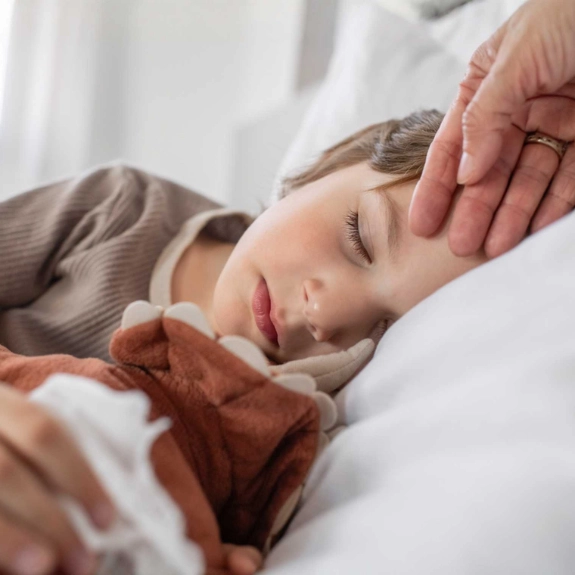 Eine Kind ist im Urlaub krank geworden. Es liegt im Bett und schläft. 