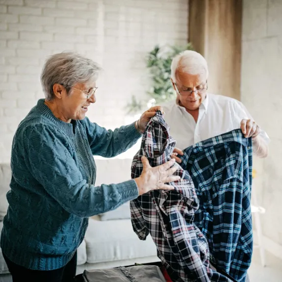 Senioriger Mann packt Kleidung in einen Koffer gemeinsam mit seiner Frau