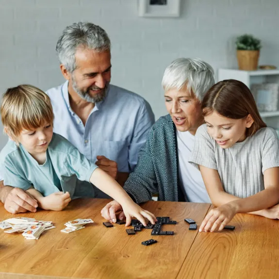 Ein älteres Paar spielt mit seinen Enkeln und denkt über die beste Möglichkeit nach, monatlich Geld für diese anzulegen.