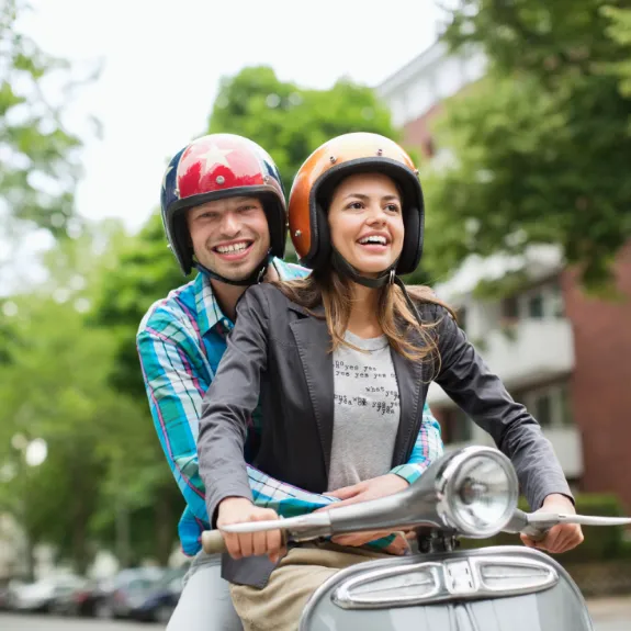 Eine Frau und ein Mann auf einem Moped haben sich über die Unterschiede von Rollern und anderen Kleinkrafträdern informiert.