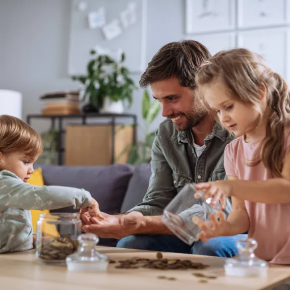 Eine Familie spart Geld in einer Spardose und nutzt im Alltag ihr Familienbudget.