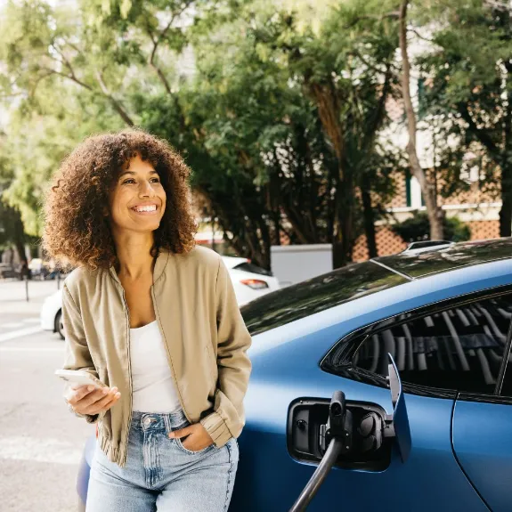 Eine Frau lädt per App ihr E-Auto unterwegs an einer Ladesäule.