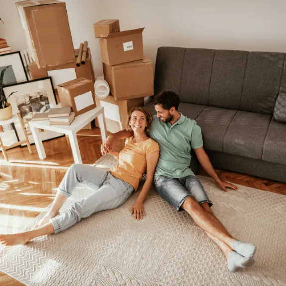 Ein junges Paar ist umgezogen und sitzt in der neuen Wohnung.