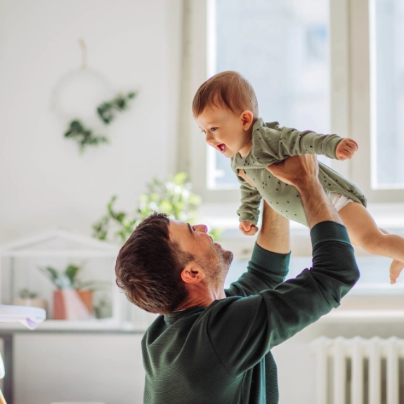Ein glücklicher Vater hebt sein Baby hoch, dessen Vaterschaft er offiziell anerkannt hat.