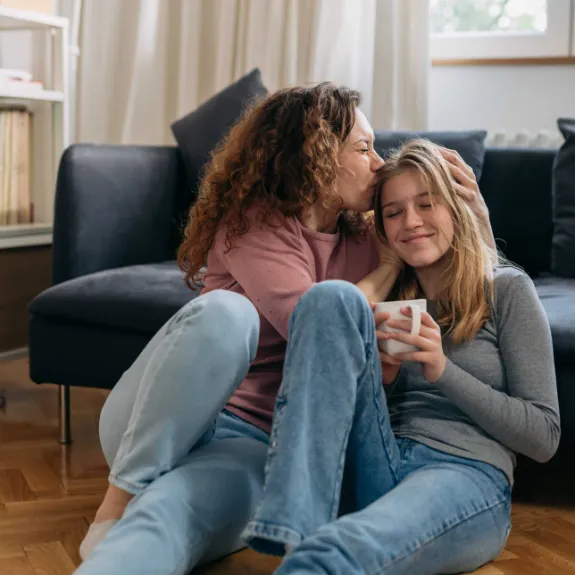 Eine Mutter umarmt ihre Tochter, die gerade in ihre erste eigene Wohnung gezogen ist.