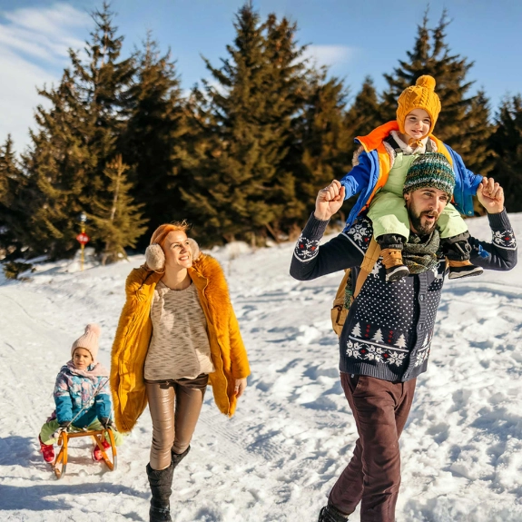 Eine Familie genießt ihren Skiurlaub und wandert mit einem Schlitten durch den Schnee.