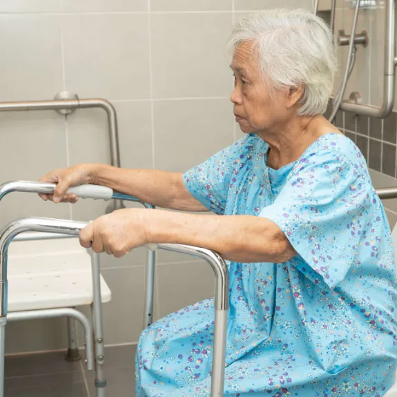 Eine alte Frau stuetzt sich im Badezimmer auf Sicherheitsgriffe