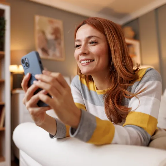Eine junge Frau informiert sich am Handy über die Leistungen der Rechtsschutzversicherung.