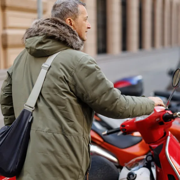 Mann fragt sich, wo er seinen Roller in der Stadt parken darf.