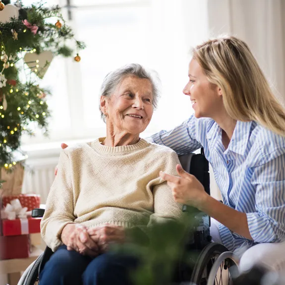 Eine Angehörige feiert Weihnachten gemeinsam mit einer pflegebedürftigen Seniorin.