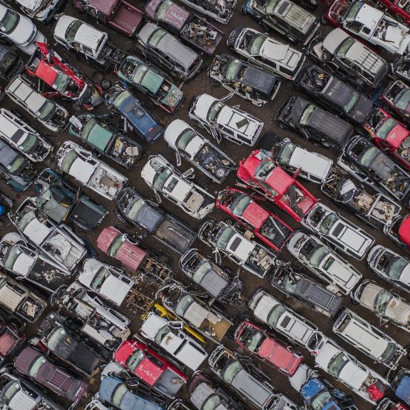 Luftaufnahme eines Schrottplatz mit beschädigten Autos in Reihen.