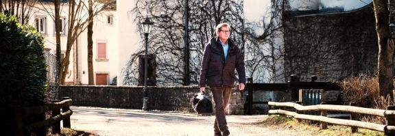 Landarzt mit Arzttasche geht eine Straße entlang.