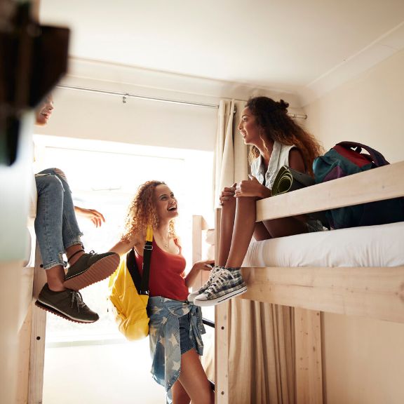 Gruppe von Jugendlichen unterhalten sich im Zimmer einer Jugendherberge