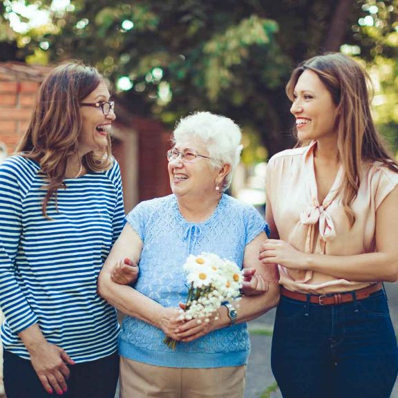 Pflege durch Angehörige Seniorin unterwegs mit ihren zwei erwachsenen Töchter.