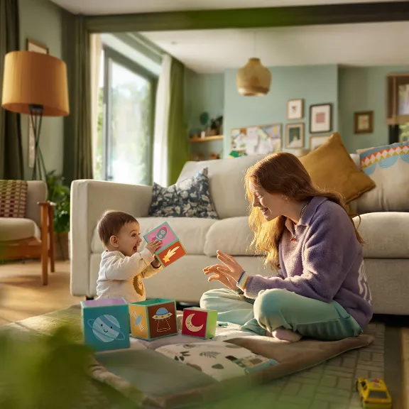 Zwei Geschwister spielen auf einem Teppich miteinander.