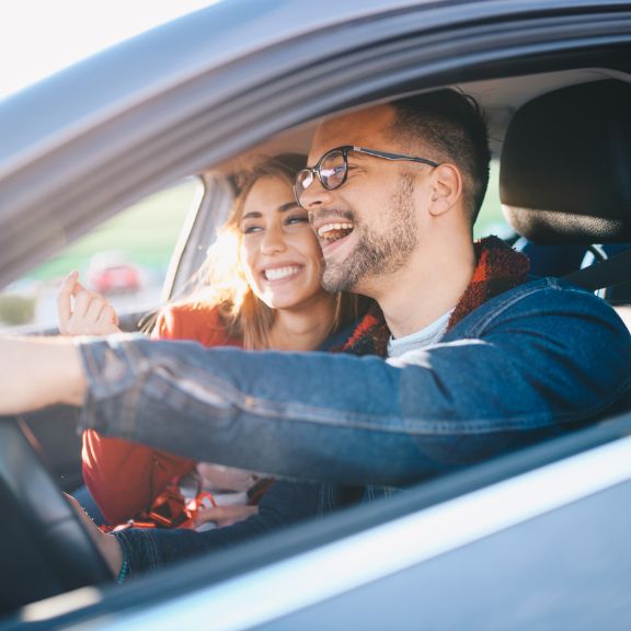 Ein Mann und eine Frau sitzen im Auto und lachen