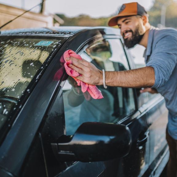 Mann wäscht Auto per Hand.