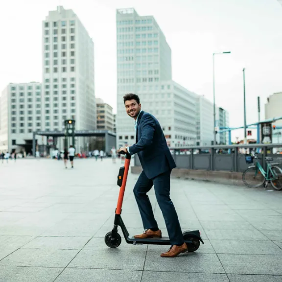 Mann fahrt auf E-Scooter auf einem Fahrradweg