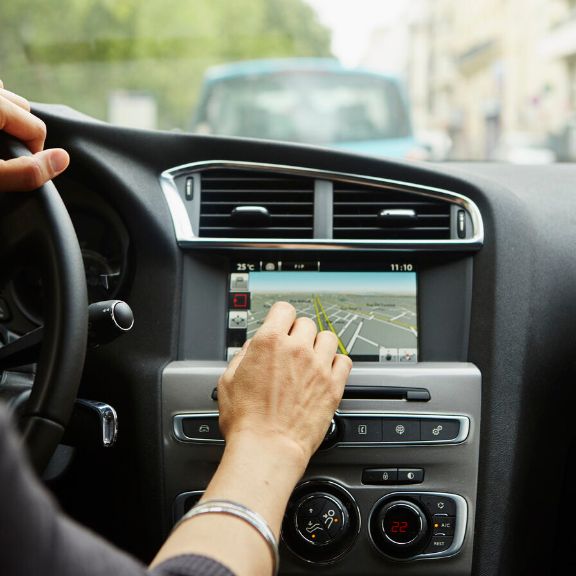 Person bedient Navigationssystem im Auto