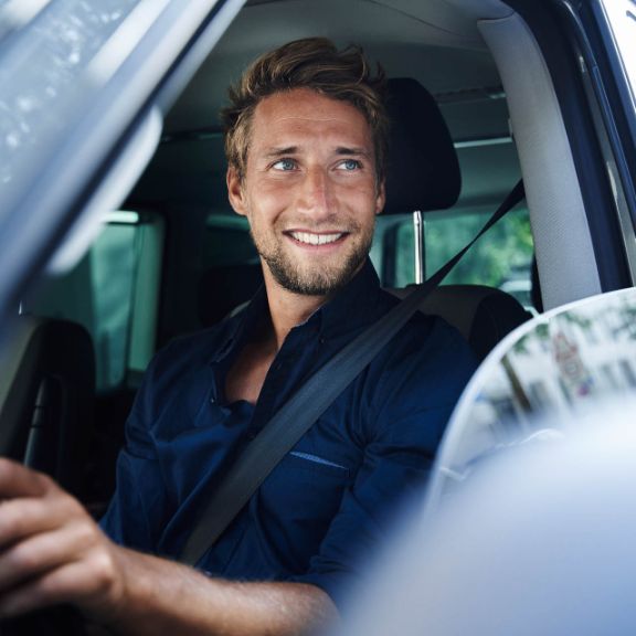 Junger Mann schaut aus dem Auto.