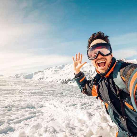 Junger Mann macht ein Selfie auf schneebedecktem Berggipfel.