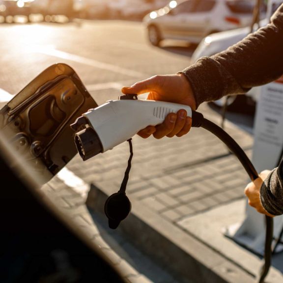 Mann lädt sein Elektroauto an Ladesäule auf.