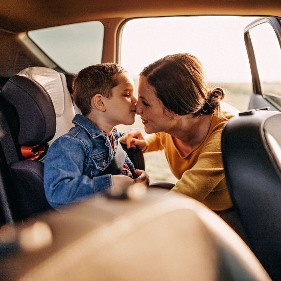 Mutter schnallt Kind im Kindersitz an.