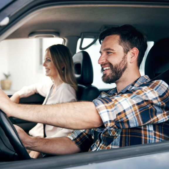 Mann und Frau fahren in einem blauen Auto.