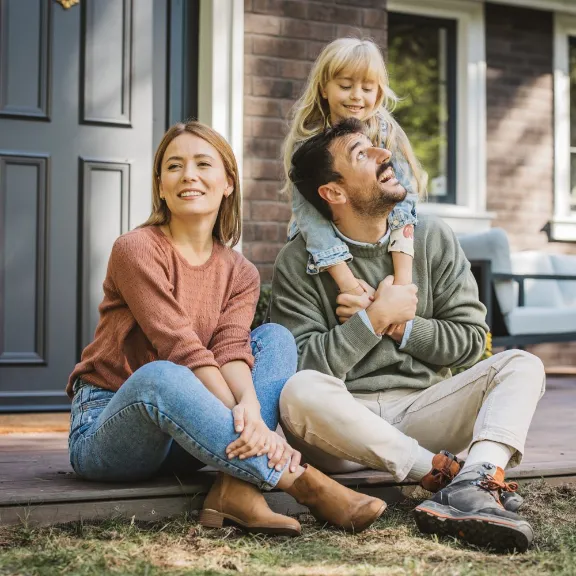 Eine Familie vor ihrem Haus freut sich über das Lösen von Rechtsstreitigkeiten durch den R+V Immobilien-Rechtsschutz.