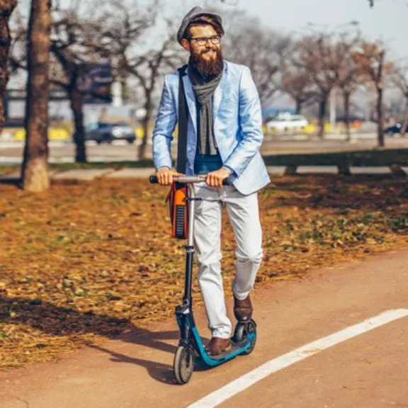Mann fahrt auf E-Scooter auf einem Fahrradweg