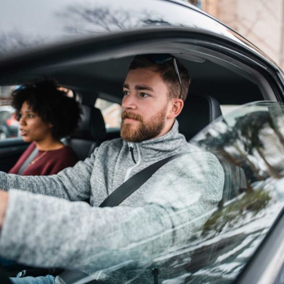 Mann und Frau fahren mit dem Auto durch die Stadt.