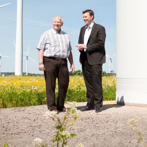 Zwei Geschäftspartner in einem Windpark.