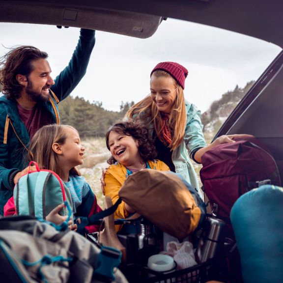 Familie packt Kofferraum Glückliche Familie packt den Kofferraum ihres Autos.