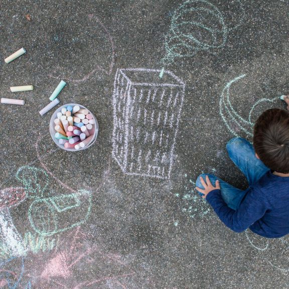 Junge malt auf der Straße mit Kreide