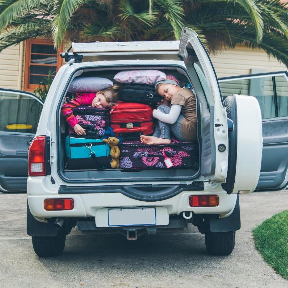 Zwei Kinder im voll beladenen Kofferraum eines Jeeps.
