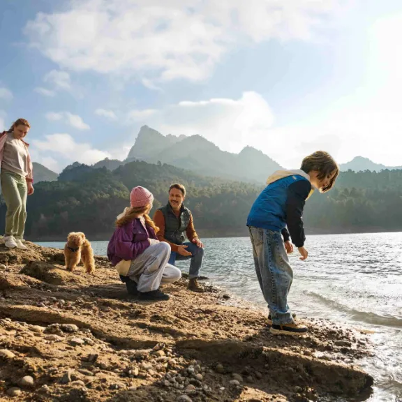 Eine Familie steht an einem See in den Bergen, als Symbol für finanzielle Absicherung.
