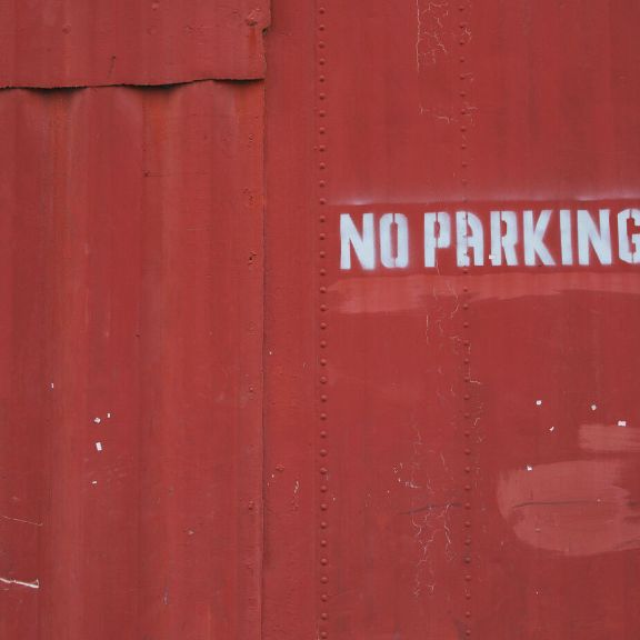Unberechtigtes Parken auf Privatgrundstück: Welche Maßnahmen sind rechtlich erlaubt? Rote Wand mit der Aufschrift NO PARKING